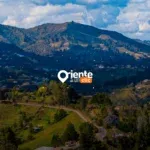 Panoramic view of a lush green valley with rolling hills and mountains under a cloudy sky.
