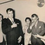 A man in a suit places his hand over his heart as others look on.