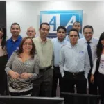 A diverse group of ten people stand together, smiling for a photo in an office setting.