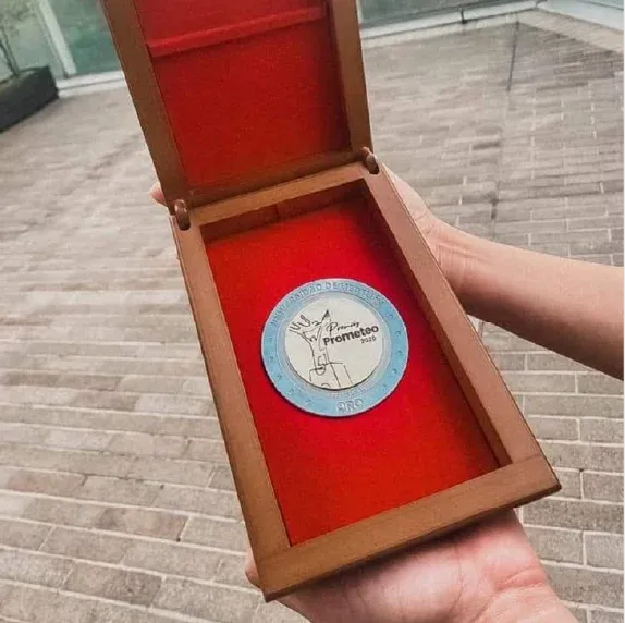 Wooden box opens to reveal a round, light blue medallion with a silhouette of a dancer.