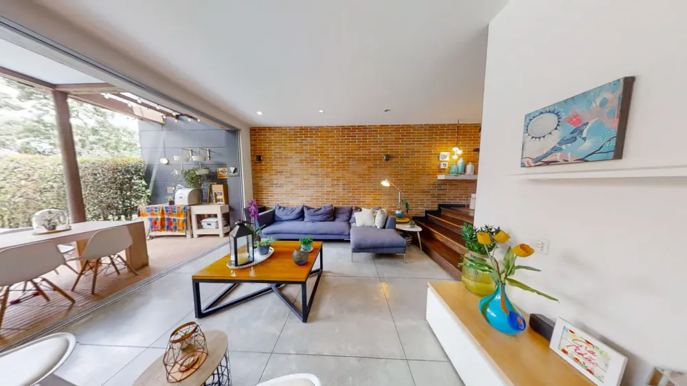 Modern living room with purple sofa, wooden coffee table, brick accent wall, and patio access.
