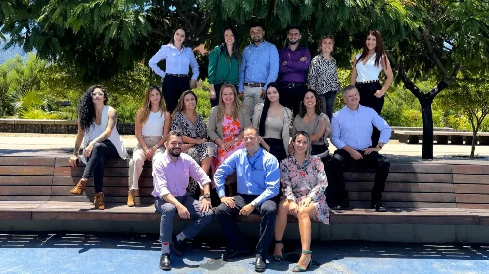 A diverse group of professionals smiles while posing outdoors on benches.