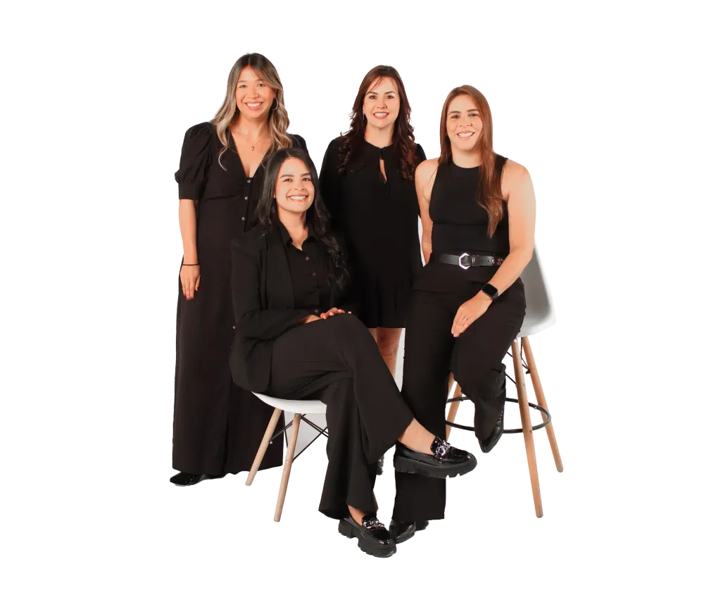 Four women in black business attire pose for a studio photograph.