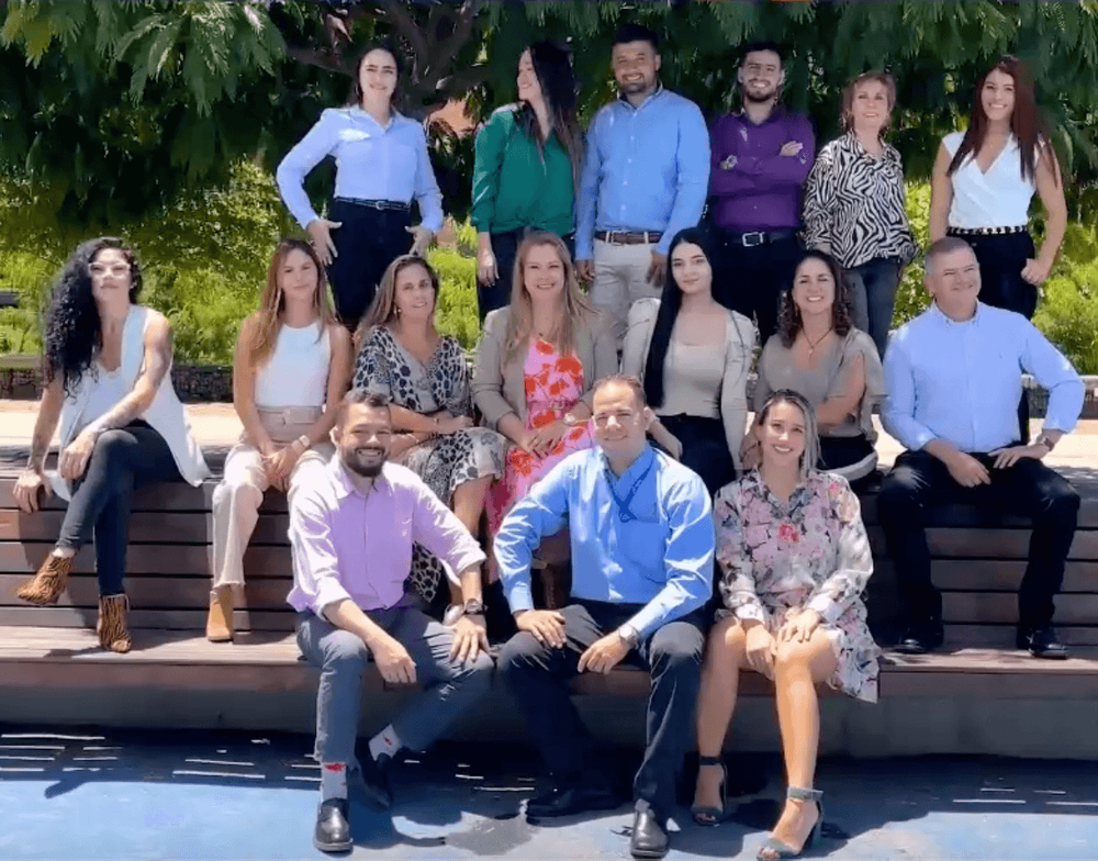 A diverse group of 14 professionals poses for a photo outdoors.