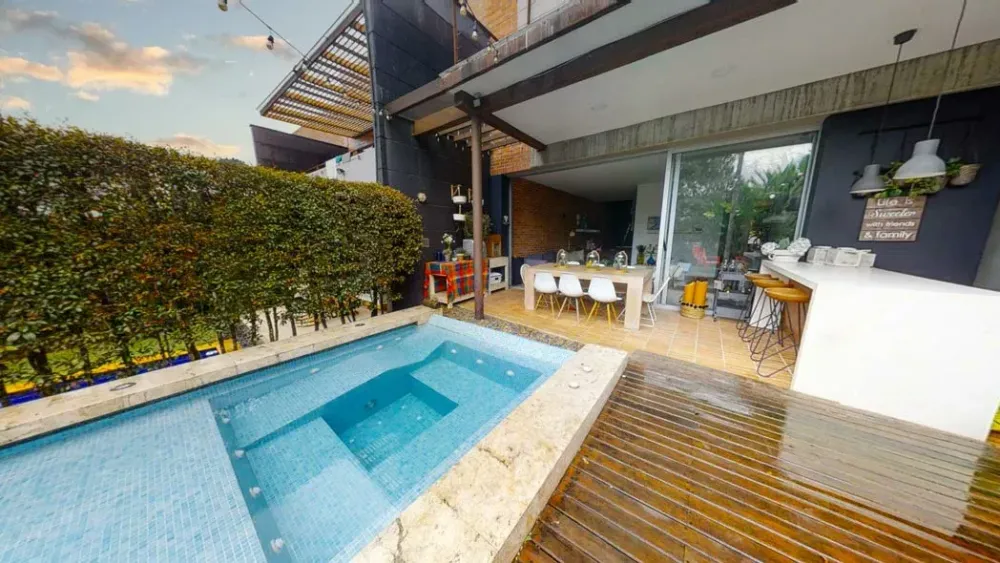 A modern outdoor living space featuring a small pool, wooden deck, and covered dining area.