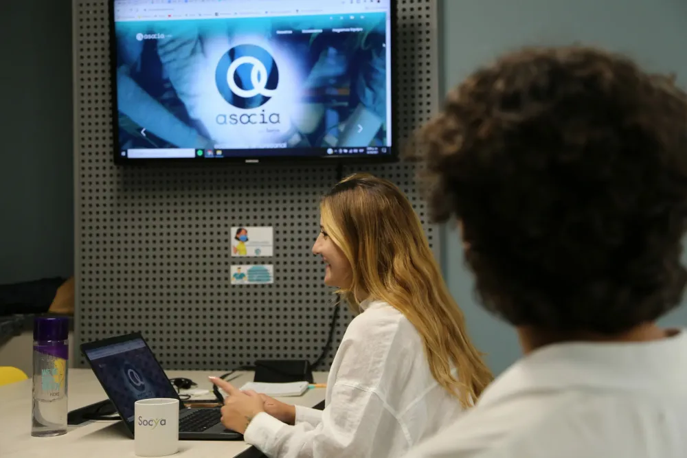 Woman smiles while looking at a laptop screen displaying the Osala.io logo.